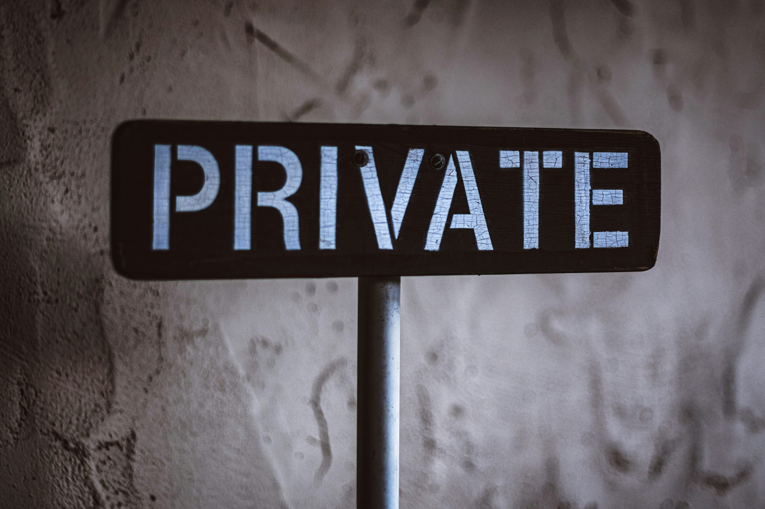 Road sign with the word private against blurred wall background